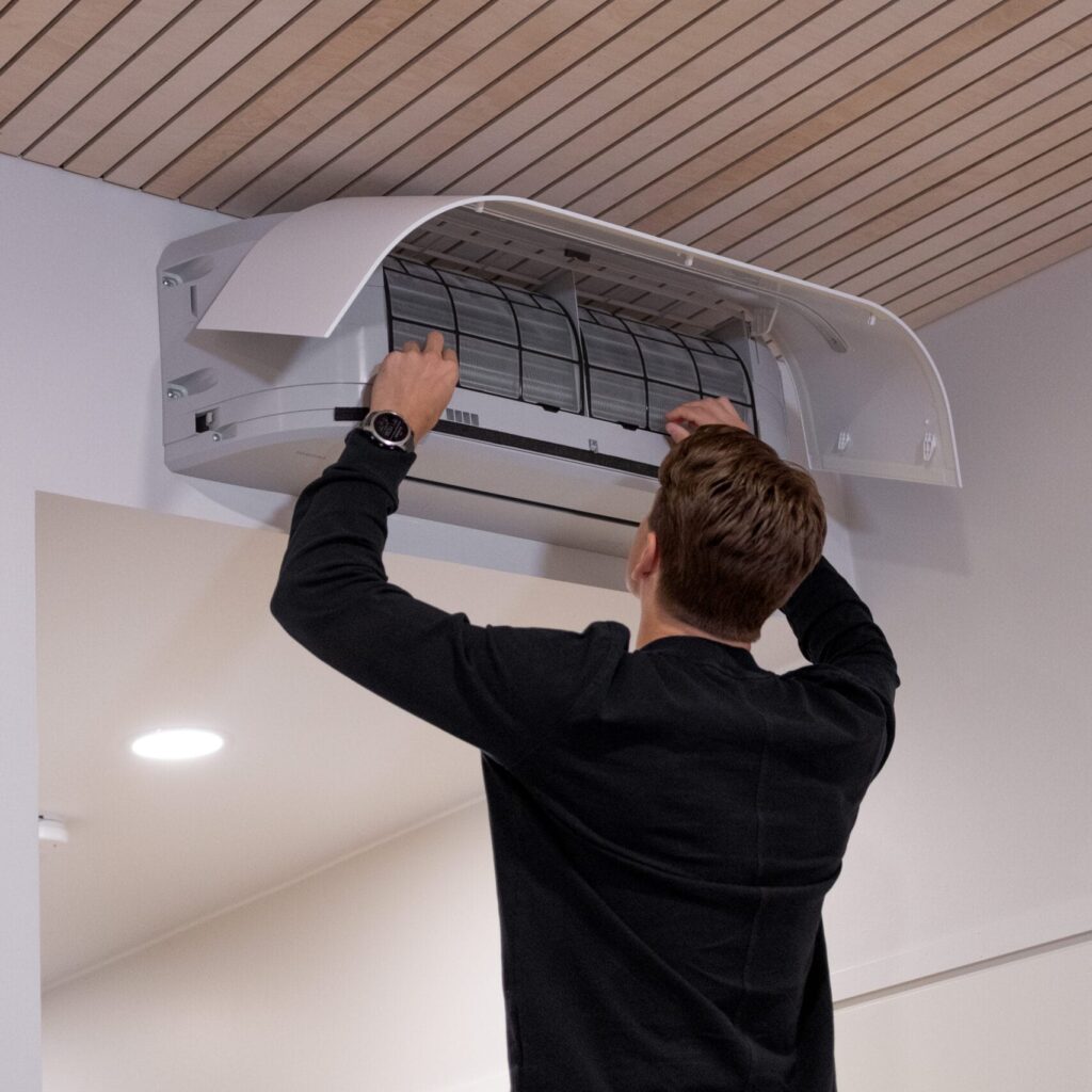 Ammattilainen huoltaa lämpöpumpun ulkoyksikköä omakotitalon pihalla – säännöllinen huolto pidentää käyttöikää