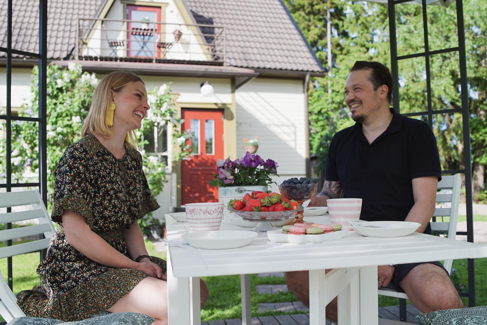 Pariskunta nauttimassa lasitetulla terassilla Oulux-ikkunoiden ympäröimänä